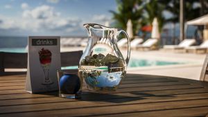 Eine Karaffe mit Wasser vor rauschendem Meer und Palmen